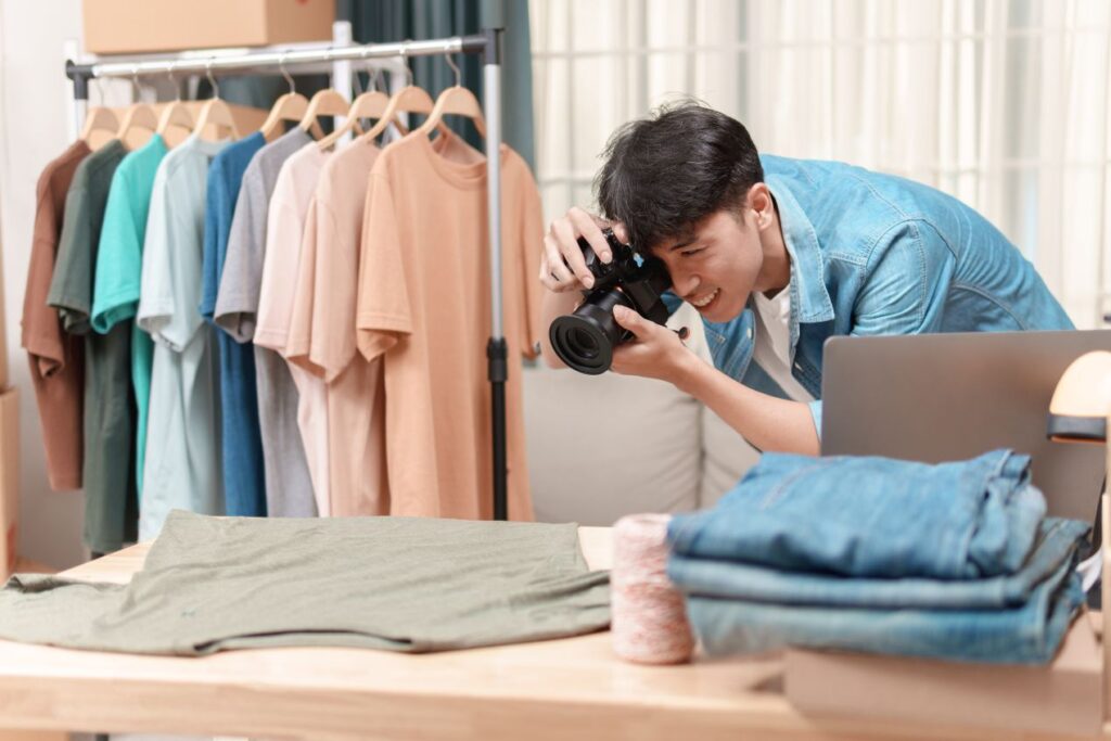 Ein Fotograf im Studio macht Amazon Produktfotos von T-Shirts, die ordentlich auf Kleiderbügeln präsentiert werden