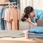 Ein Fotograf im Studio macht Amazon Produktfotos von T-Shirts, die ordentlich auf Kleiderbügeln präsentiert werden
