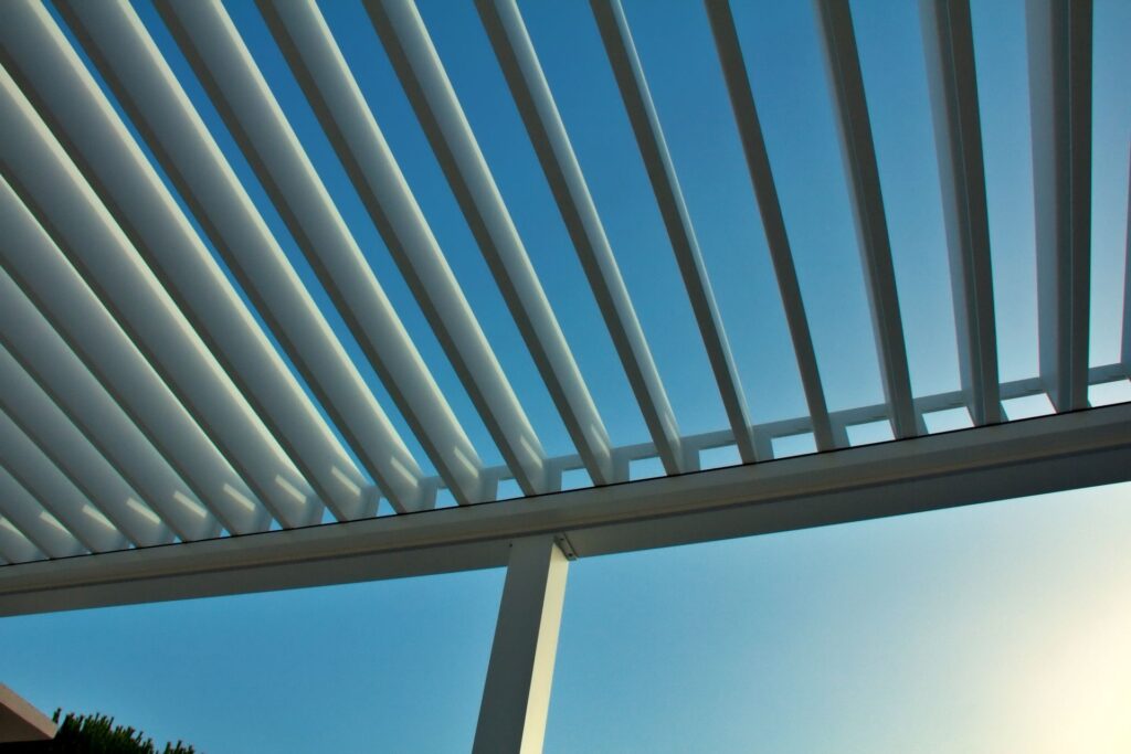 Detailaufnahme einer modernen Lamellen-Terrassenüberdachung aus Aluminium mit blauem Himmel